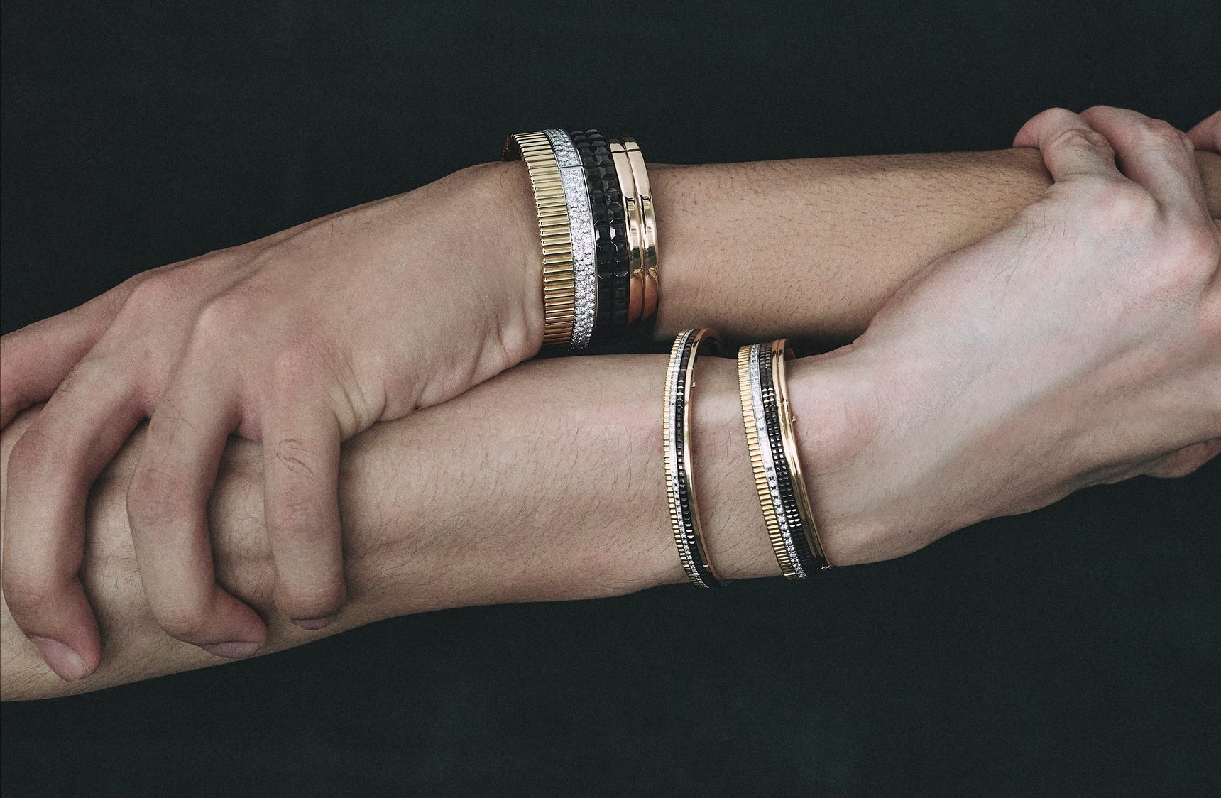 Crossed arms of two models wearing gold and black bangles – Emporio Models