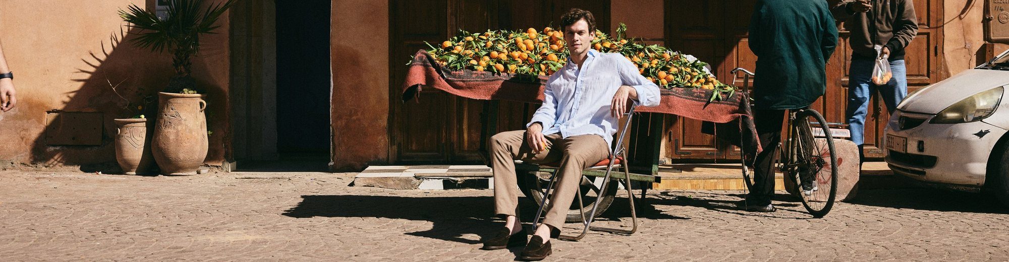 Model seated beside an orange cart in Marrakech – contact Emporio Models Marrakech