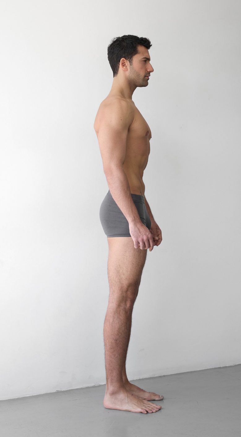 Digital en pied d’un mannequin homme, vue de l’autre profil, devant un mur uni