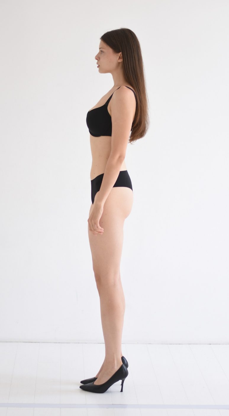 Digital en pied d’une mannequin femme, vue de profil, devant un mur uni